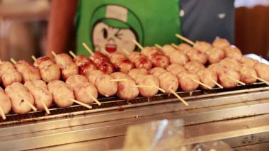 Satıcı, yüzen markette ızgara sosis yapıyor.