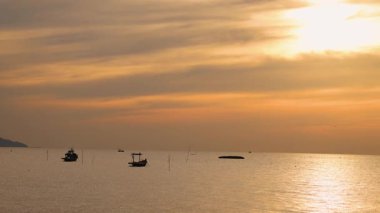Canlı bir günbatımına karşı gölgeli tekneler