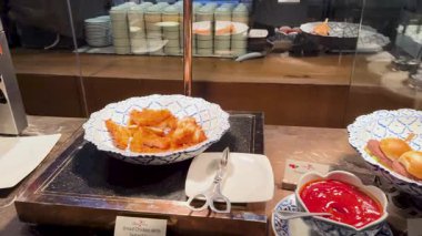 Açık büfe, iyi aydınlatılmış bir restoran ortamında taze gıdayla doldurulur ve dinamik bir yemek deneyimi sergiler.