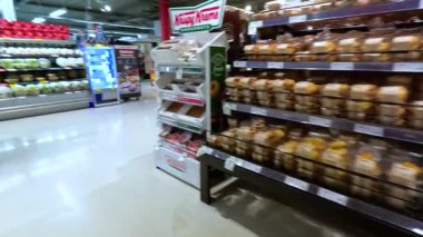 Kalabalık bir Melbourne süpermarketinin gezintisi çeşitli koridorları, ürünleri ve müşterileri iyi aydınlatılmış bir çevrede sergiliyor.