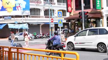 Yayalar ve araçlar Phuket, Tayland 'da hareketli bir kavşakta yol alıyorlar. Parlak gün ışığı canlı şehir ortamını aydınlatır