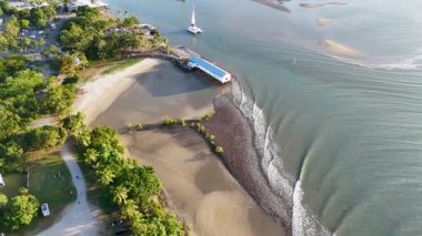 İnsansız hava aracı, sakin bir sahil beldesini süzülerek, yemyeşil ve sakin suları gösteren bir yelkenliyle yakalıyor.