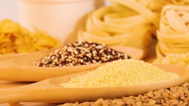 Parlak ışık altında rengarenk tanecikler, makarna ve ekmek dilimleri, çeşitli dokular ve renkler sergileniyor.