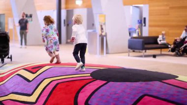 Çocuklar müze lobisinde neşeyle koşuyorlar.