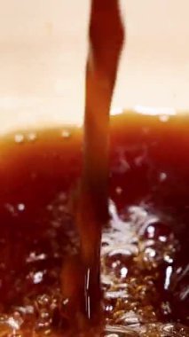 Kahve bardağa doldurulur, yakın çekim görüntüsünde köpük ve kabarcıklar oluşturur.