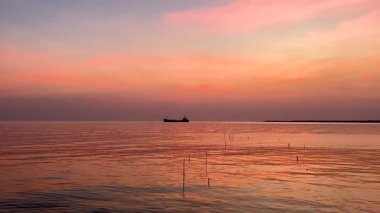 Uzak bir gemiyle huzurlu gün batımı manzarası