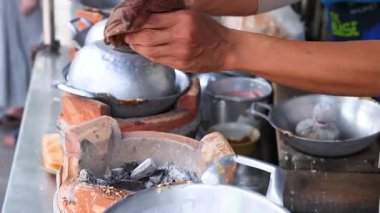 Eller Phuket, Tayland 'da bir sokak yiyecek standında hindistan cevizi atıştırmalıkları hazırlıyor. Parlak ışıklandırma geleneksel yemek pişirme sürecini vurguluyor