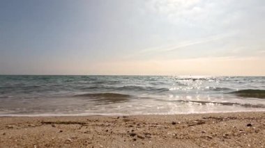 Güneşli bir sahilde hafif dalgalar.