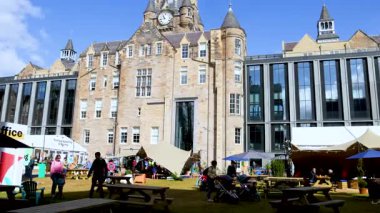 İnsanlar üniversitede güneşli bir günün tadını çıkarıyorlar.