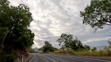 Port Douglas, Queensland 'daki bulutlu gökyüzü altında yemyeşil ve kıyı manzaraları boyunca sakin bir yolculuk.