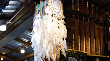 Bir düş kapanı canlı bir Phuket pazarında sallanıyor. Ilık ışıkla aydınlatılıyor ve ahşap yapılarla çevrili.