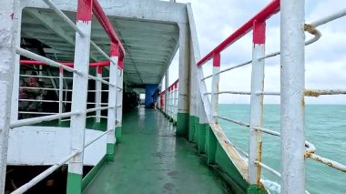 Koh Samui kıyısı boyunca sakin bir feribot yolculuğu, canlı korkuluklar ve bulutlu gökyüzünün altında geniş okyanus manzaraları sergiliyor.