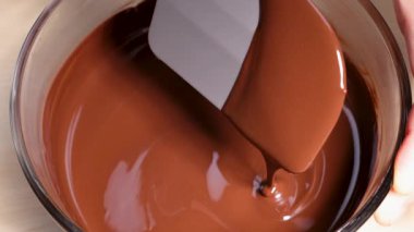 Spatula kaymaklı çikolatayı berrak cam kasede eritiyor.