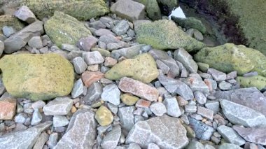 Bir kamera kayalık bir kıyı mağarasında döner, dokulu duvarları ve doğal ışık altındaki dağınık taşları ortaya çıkarır.