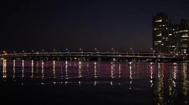 Illuminated bridge reflecting on water at night