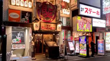 Canlı neon ışıklı bir sokakta yürüyen yayalar.