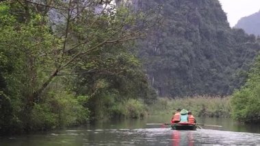 İnsanlar sakin bir nehir manzarasında kürek çekiyorlar.