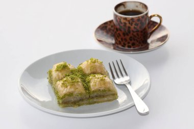 Lezzetli Türk Pistachio Baklava ve bir fincan Türk kahvesi beyaza izole edilmiş.