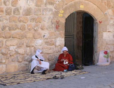 MIDYAT, MARDIN, TURKEY-ECTOBER 09: Evlerinin önündeki halıda oturan tanımlanamayan Kürt Kadınlar. 09 Ekim 2021, Midyat, Türkiye