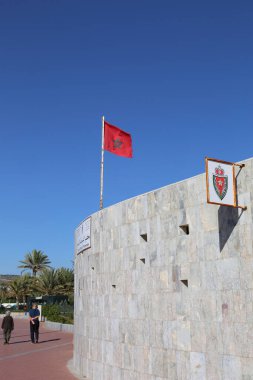 AGADIR, MorOCCO-ARALIK 11 Aralık 2015: Güneşli bir kış gününde Sahil Polis Karakolu 'nun önünden yürüyen kimliği belirsiz yaşlı çift