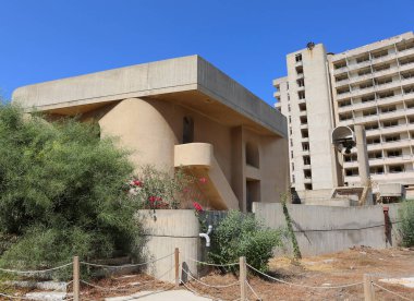 VAROSHA, FAMAGUSTA, NORTH CYPRUS-AĞUSTust 30. 2023: Terk Edilmiş Eski Kilise ve Mavi Gök ile Otel Binası