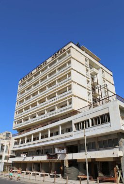 Varosha, Famagusta, Kuzey Kıbrıs - 30 Ağustos 2023: Sıcak Bir Yaz Günü 'nde Eski Terk Edilmiş Otel ve İş Dünyasında yürüyen Tanımlanamayan İki Adam