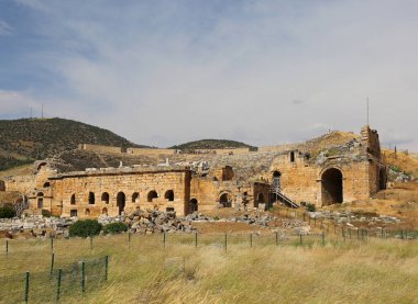 PAMUKALE, DENIZLI, TURKEY-MAYIS 22.2022: Mavi Gökyüzü Arkaplanlı Antik Hierapolis Roma Amfitiyatrosunda oturan tanımlanamayan turistler 
