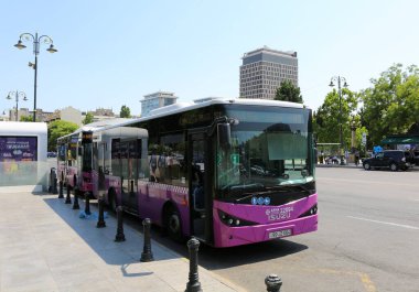 BAKU, AZERBAIJAN-JUNE 30. 2024: Otobüs durağında bekleyen otobüsler ve kimliği belirsiz kişiler