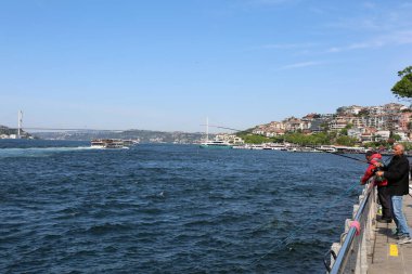 ISTANBUL, TURKEY-MAYIS 11.2022: Deniz feneri tarafından Uskudar sahilinde balık tutan tanımlanamayan balıkçılar