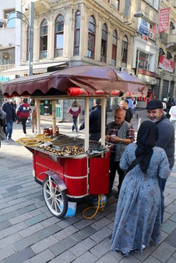 İSTANBUL, TURKEY-NOVEMBER 08.2021: Kimliği belirsiz müşteriler Istiklal Bulvarı 'ndaki bir satıcıdan kestane alıyor