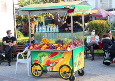 BUYUKADA, İSTANBUL, TURKEY-NOVEMBER 05.2021: Etrafında renkli lezzetli meyveler ve tanımlanamayan insanların oturduğu meyve arabası