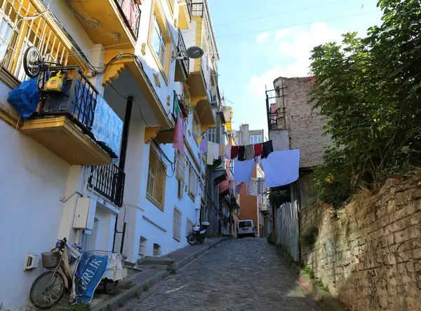 İSTANBUL, TURKEY- 11 Kasım 2021 Scooter, Bisiklet, Araba, İncir Ağacı ve Çamaşır ile Renkli Eski Sokak