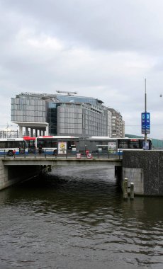 AMSTERDAM, NETHERLANDS-MARCH 01,2014:Dutch Public Buses driving on The Bridge by the Doubletree by Hilton Hotel  clipart