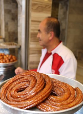 ADANA, TURKEY-OCTOBER 23,2018:Unidentified Dessert Shop Employee waiting to sell Traditional Adana Dessert Sari Burma aka Turkish Churro clipart