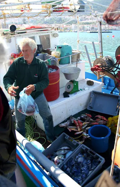 Samos, Yunanistan-Nisan 03.2006: Kimliği belirsiz balıkçı avını sabahın erken saatlerinde teknesinde satıyor