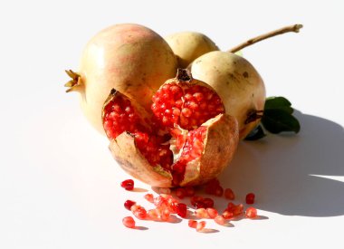 Olgun organik nar meyveleri ve beyaz üzerine izole tohumlar.