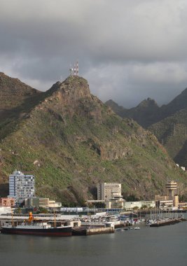 Tenerife, İspanya-12 Aralık 2014: Dağları, bulutları, gemisi, botları ve limandaki binaları olan İspanyol Adası