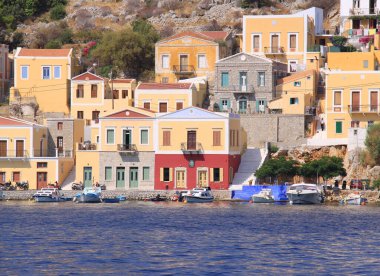 Symi, Yunanistan-Temmuz 14. 2013: Teknelerle deniz kenarındaki renkli Yunan evleri arasında yürüyen tanımlanamayan adam