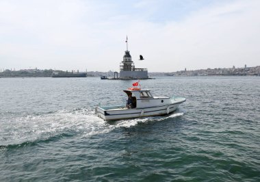 İstanbul, Türkiye-11 Mayıs 2022: Türk Bayrağı ve Kimliği belirsiz Kaptanı ile küçük balıkçı teknesi Kiz kulesi namı diğer Bakire Kulesi 'nden geçiyor