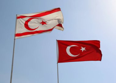 Kuzey Kıbrıs Ulusal Bayrağı ve Türkiye Cumhuriyeti, Kuzey Kıbrıs Rum Kesimi, Varosha, Famagusta 'da mavi gökyüzü arkaplanıyla havada dalgalanıyor