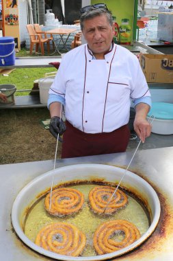 Adana, Türkiye-10 Nisan 2025: Kimliği belirlenemeyen Aşçı Türk Churros 'u kızartıyor nam-ı diğer Halka Tatlılar Portakal Çiçeği Festivali' nde