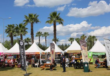 Adana, Türkiye-10 Nisan 2025: Tanımlanamayan İnsanlar Geleneksel Portakal Çiçeği Festivali 'nde Palmiye Ağaçları ve Satıcıları tarafından tatlı yiyecekler yiyor