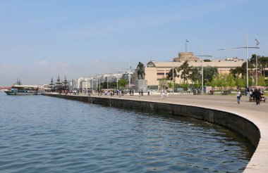 Selanik, Yunanistan-23 Nisan 2025: Ege Denizi kıyısındaki Halk Yürüyüşü alanında Kule, Heykel ve Gemilerle Tanımlanamayan İnsanlar