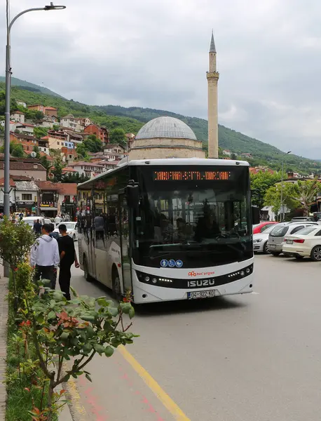 Prizren, Kosova-30 Mayıs 2025: Yolcuları, yürüyen insanları ve Arkaplanda Sinan Paşa Camii olan renkli binaları olan halk otobüsü