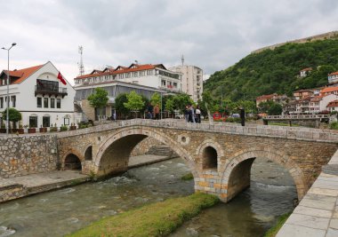 Prizren, Kosova-30 Mayıs 2025: Nehir üzerindeki Eski Taş Köprüsü, Türkiye Konsolosluğu ve Arkaplanda Türk Bayrağı ve Binaları Üzerinde Tanımlanamayan İnsanlar