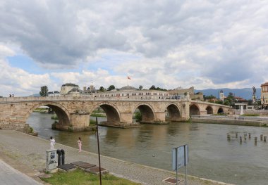 Üsküp, Kuzey Makedonya-28 Mayıs 2025: Kimliği belirsiz bazı kişiler Taş Köprü 'de yürürken, bazıları Vardar Nehri' nin kenarında fotoğraf çekiyor