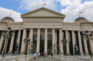 Üsküp, Kuzey Makedonya-28 Mayıs 2025: Tanımlanamayan İnsanlar Arkeoloji Müzesi önünde yürüyor ve bisiklete biniyor