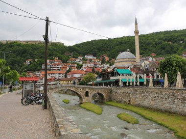 Prizren, Kosova-30 Mayıs 2025: Bisikletine binen adam ve Taş Köprü 'den geçen diğer adamlar 