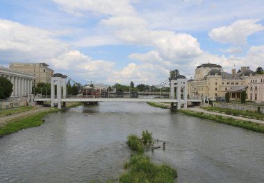 Üsküp, Kuzey Makedonya-28 Mayıs 2025: Tanımlanamayan İnsanlar Vardar Nehri 'ndeki Sahte Korsan Gemisi ile Müze Binaları arasında köprüden geçiyor