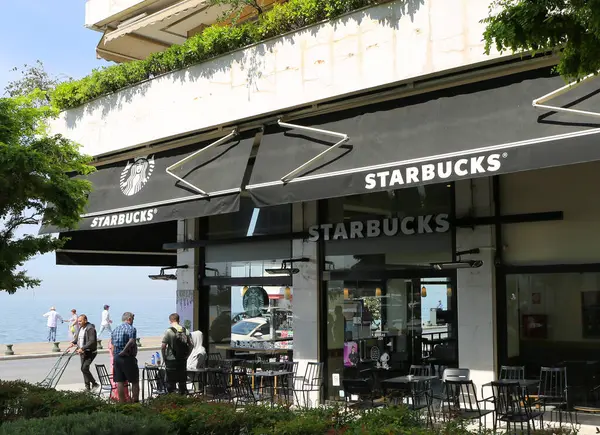 Selanik, Yunanistan-23 Nisan 2025: Kimliği belirsiz kişiler Ege Denizi kıyısındaki Starbucks Kahve Evi 'nde balık tutuyor, ayakta duruyor ve oturuyorlar